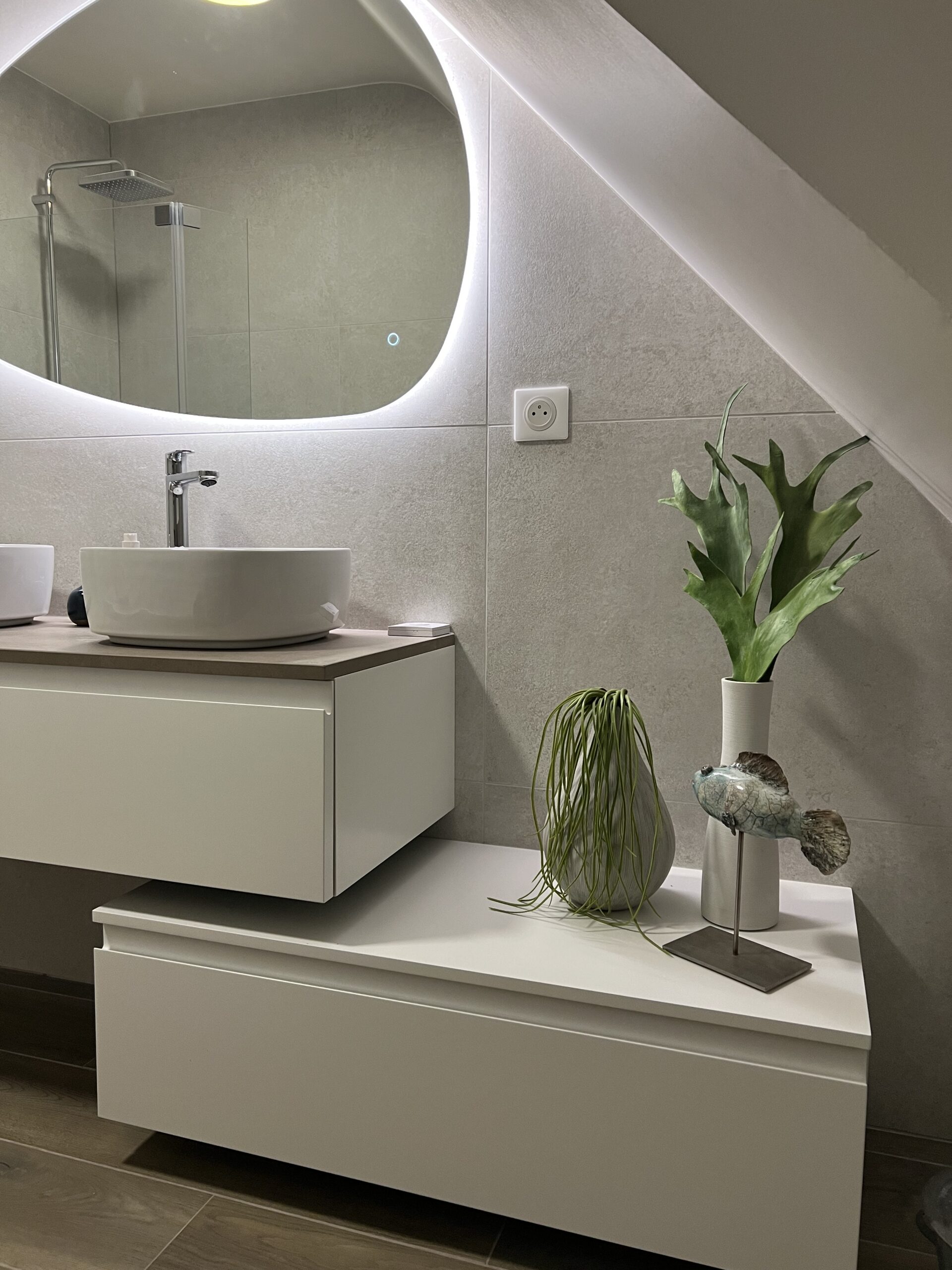 Salle de bain sous rampant à Orvault, meuble blanc, vasque Roca et miroir organique rétroéclairé