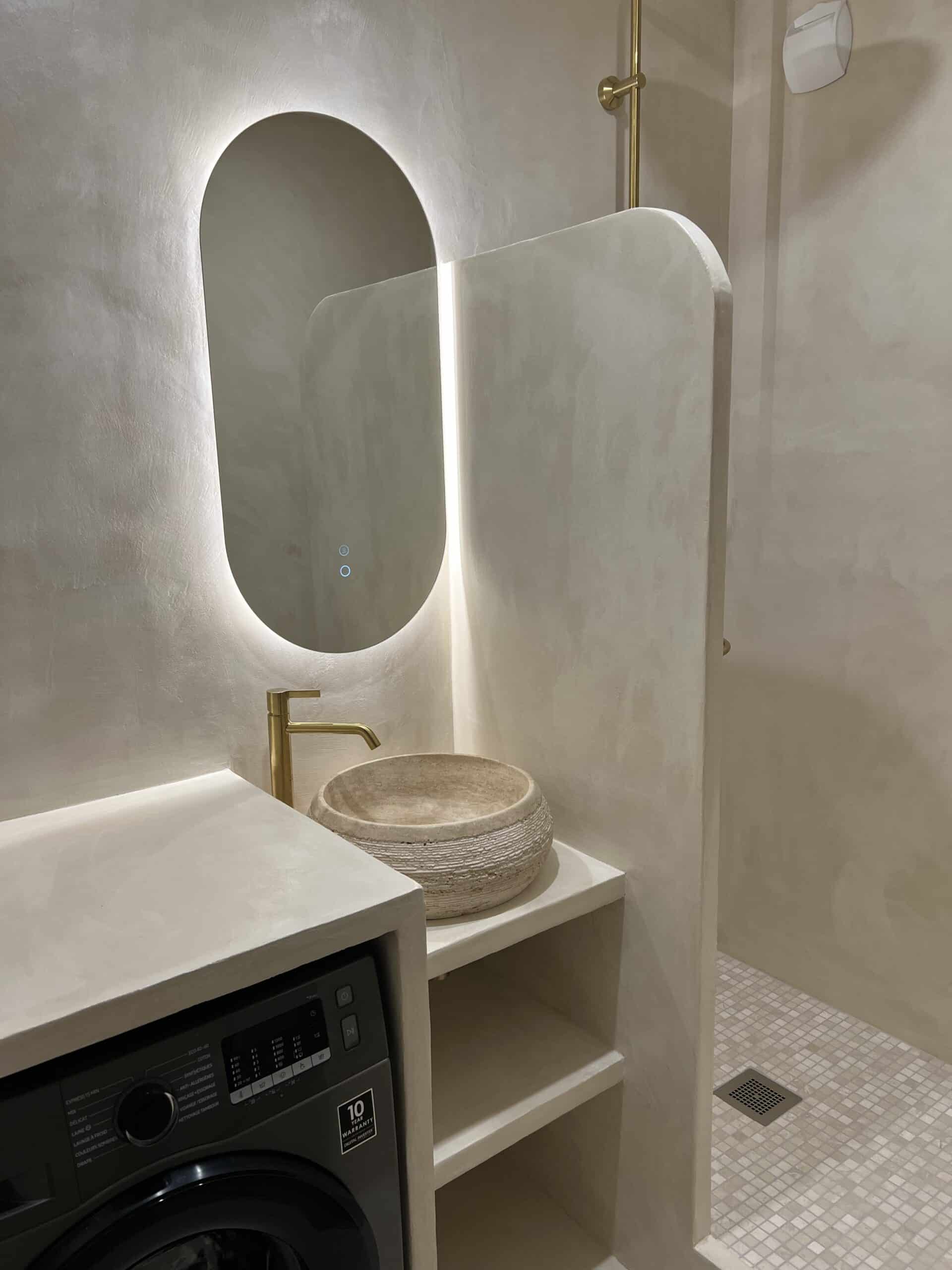 Salle de bain en béton ciré à Nantes, vasque en pierre, robinetterie en laiton et lave-linge intégré sous la vasque